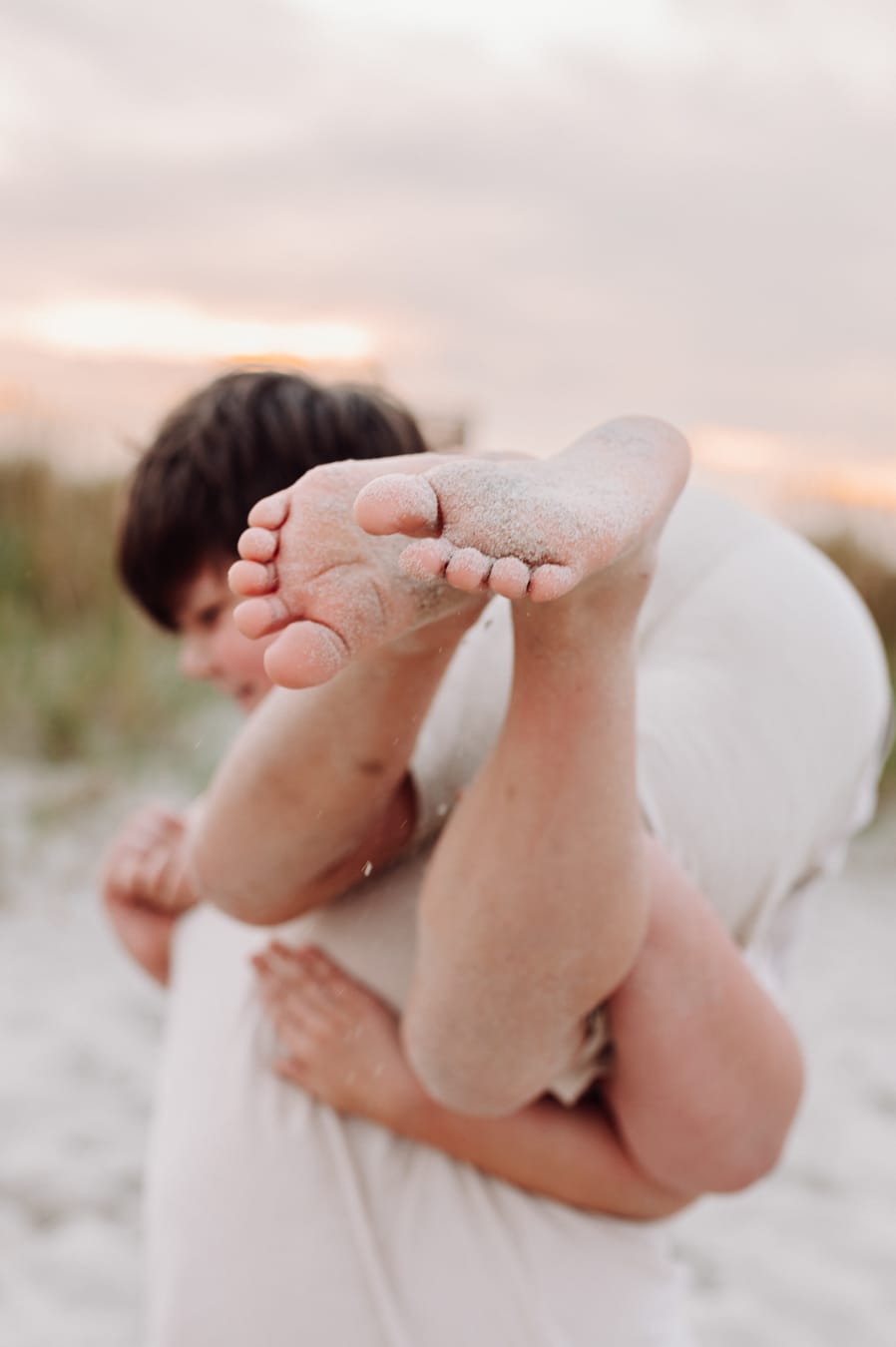 Nastolatek dźwiga młodszego brata na plaży sesja rodzinna Trójmiasto
