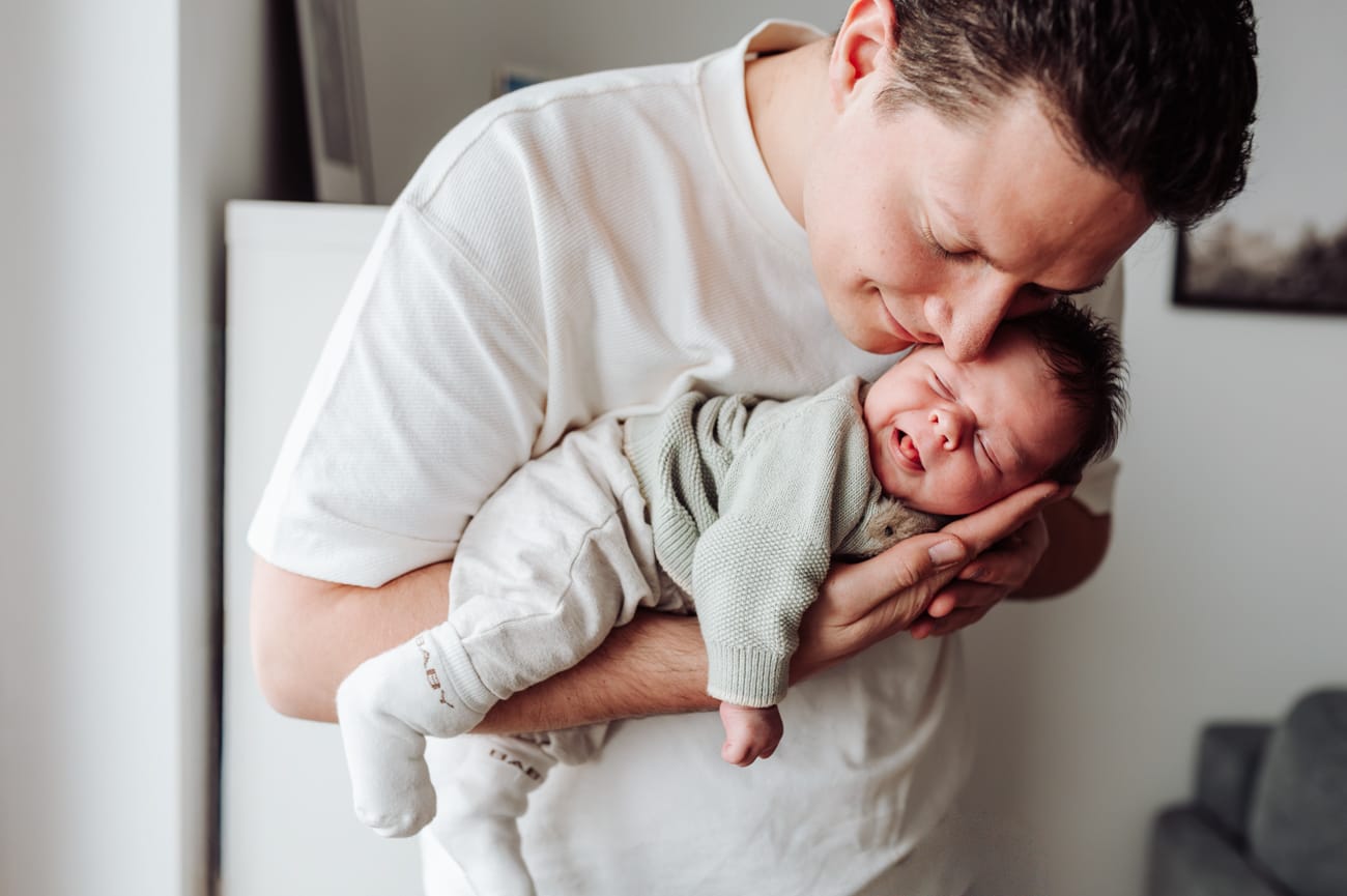 Domowe zdjęcia noworodka lifestyle tata trzyma uśmiechnięte dziecko na rękach, Gdańsk Gdynia Sopot.