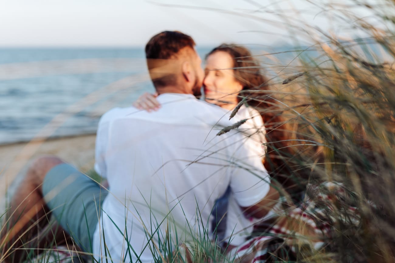Para siedząca na plaży wśród nadmorskich traw sesja narzeczeńska Rewa
