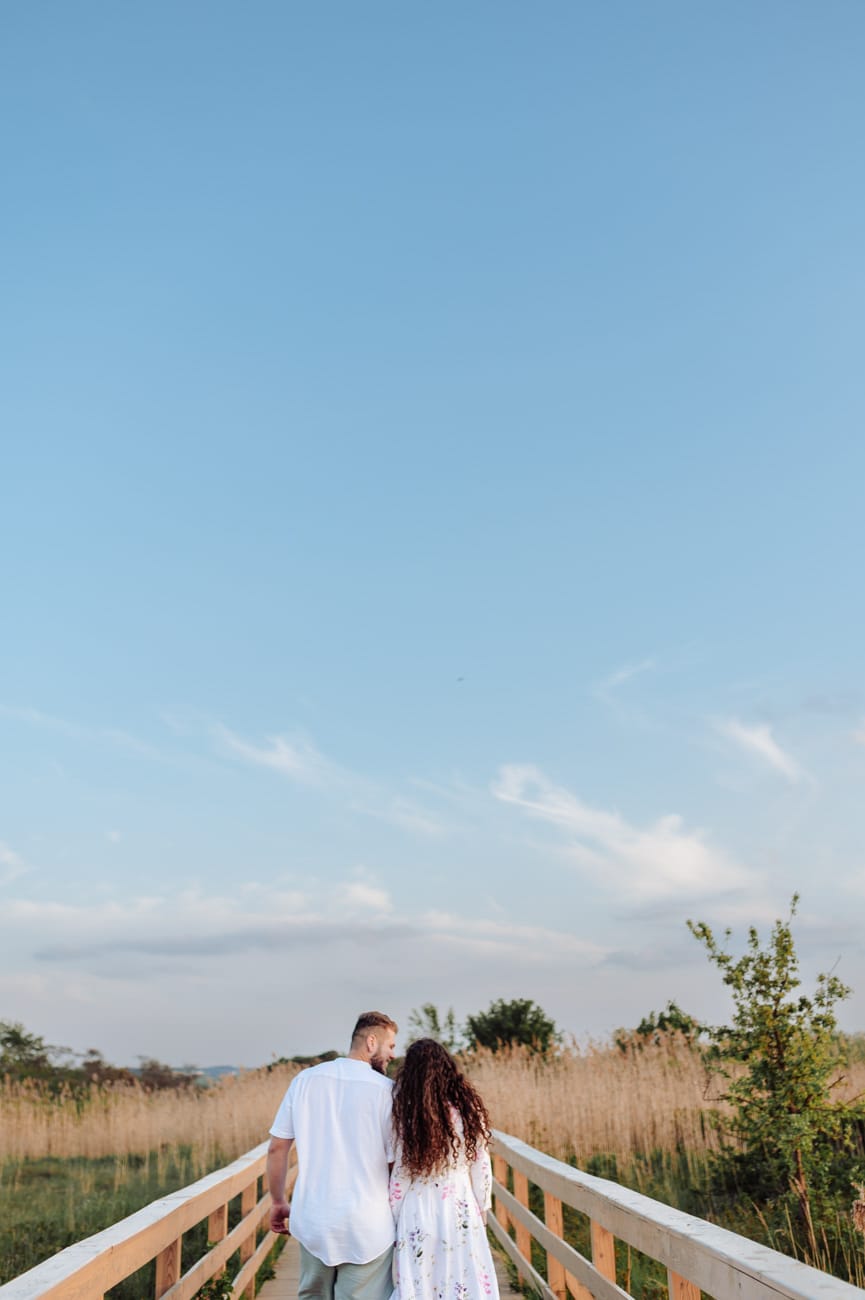 Para idzie drewnianą kładką nad łąkami sesja narzeczeńska
