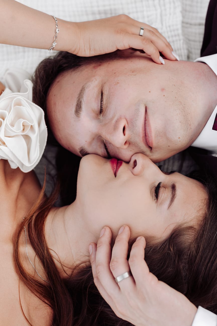 Młoda para przytula się leżac na kocu sesja poślubna nad morzem