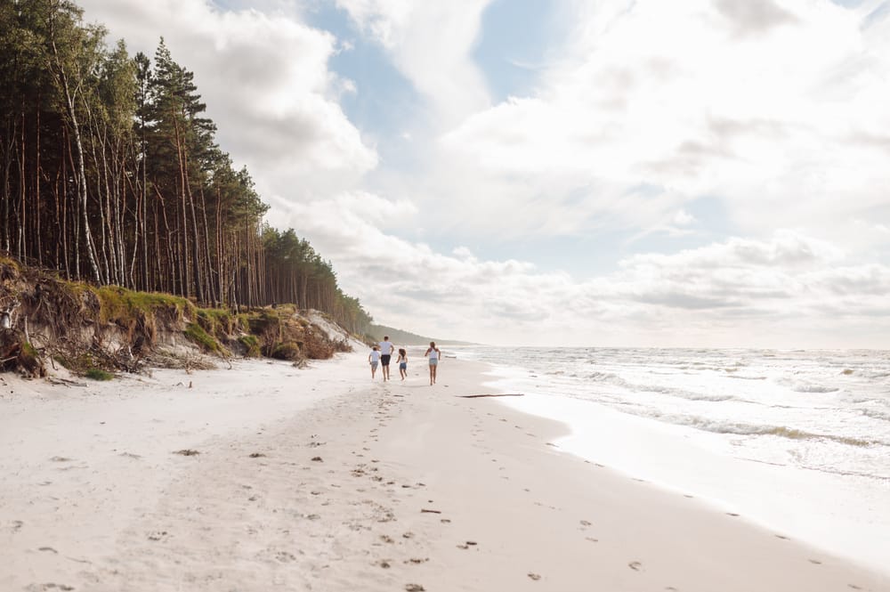 Rodzina biegnąca wzdłuż morza w ciepły letni dzień — sesja rodzinna Trójmiasto