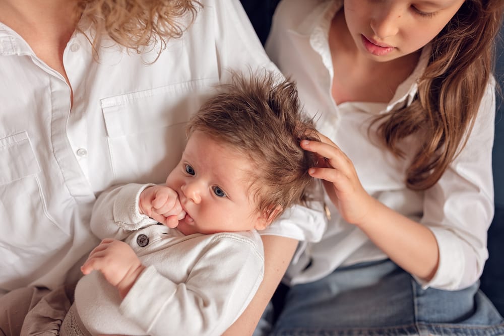 Sesja rodzinna z psem w domu Gdańsk siostra głaszcze niemowlaka