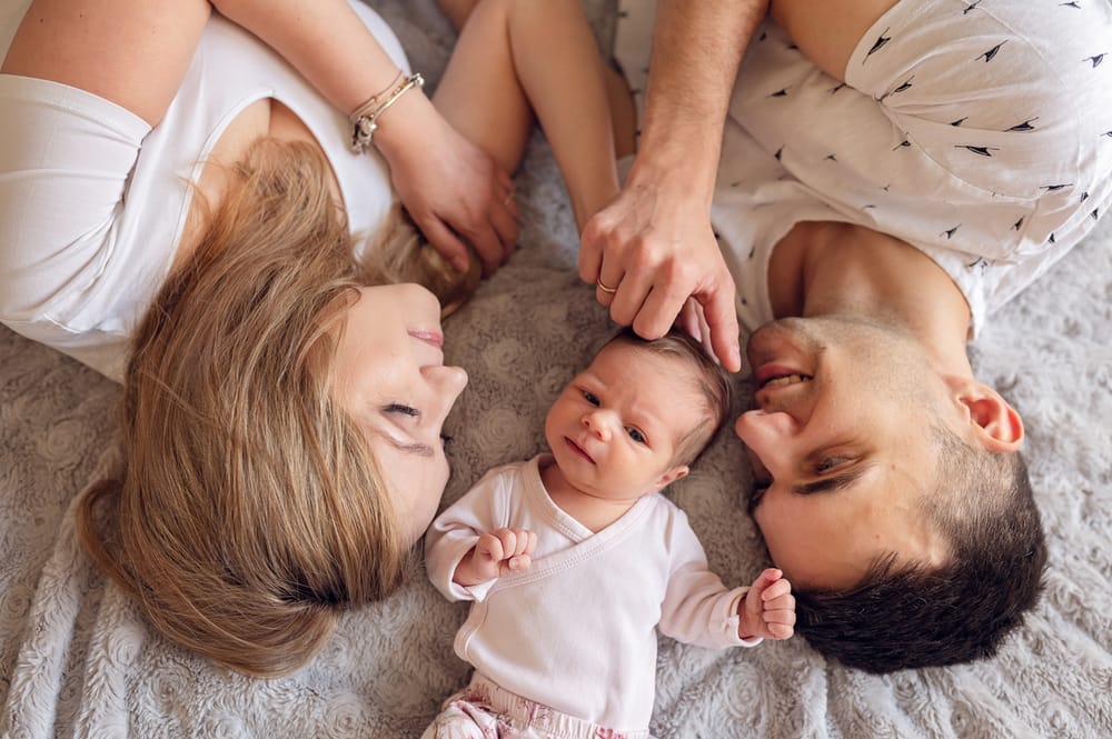 Sesja noworodkowa w domu Gdańsk rodzina z noworodkiem na łóżku