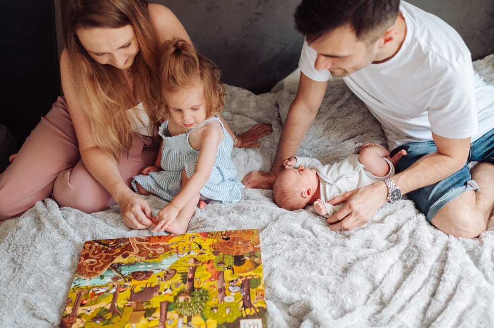 Sesja noworodkowa z rodzeństwem w domu Gdańsk siostra czyta książkę