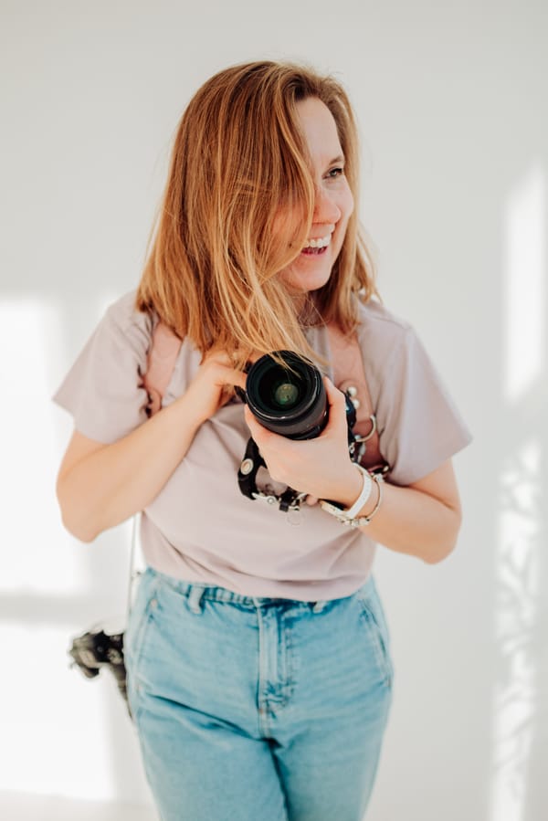 Natalia Kobylak fotografka z aparatem śmiejąca się z rozwianymi włosami — fotografia lifestyle Trójmiasto