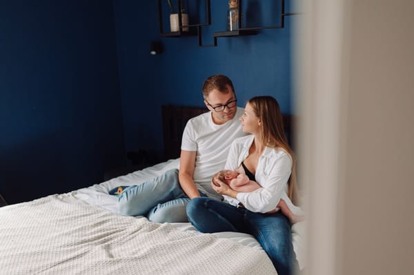 Rodzinny kadr z noworodkiem karmionym piersią w sypialni podczas sesji noworodkowej w Gdańsku