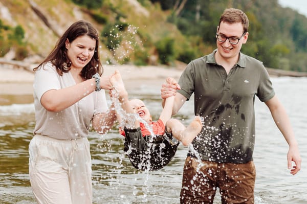 Rodzina bawiąca się z synkiem w wodzie na plaży podczas sesji rodzinnej w Gdyni