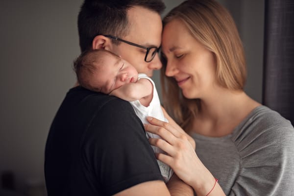 Jak przygotować dom do sesji noworodkowej rodzice z noworodkiem przy oknie