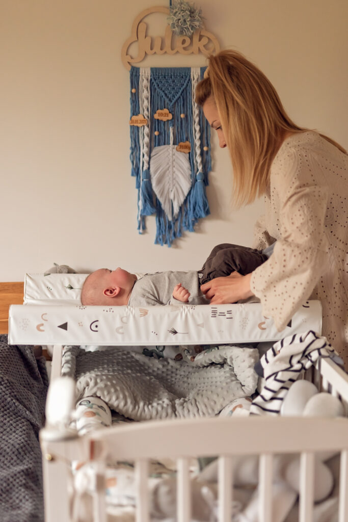 Niemowle na przewijaku a nad nim łapacz snów z imieniem.