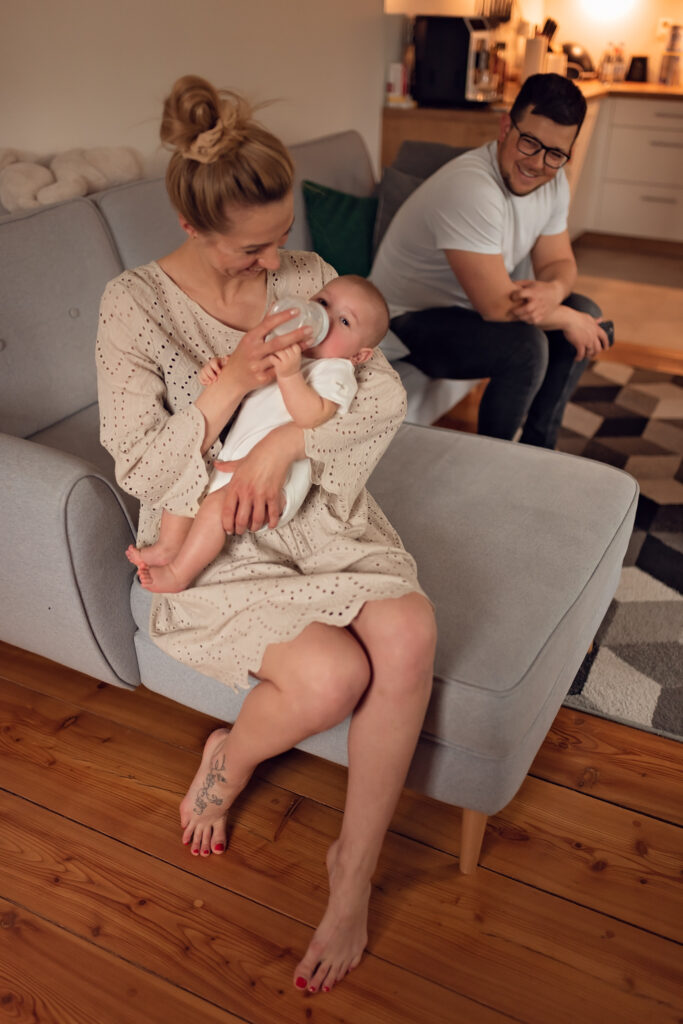 Mama karmiąca butelką niemowlaka w domowym zaciszu.