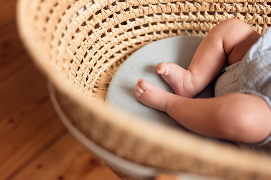Stópki niemowlaka w koszu mojżesza w domowym zaciszu.
