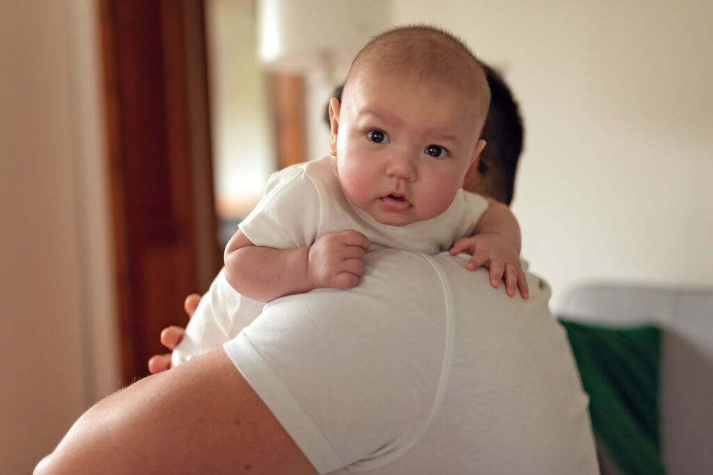 Niemowle na ramieniu taty odbijane po karmieniu.