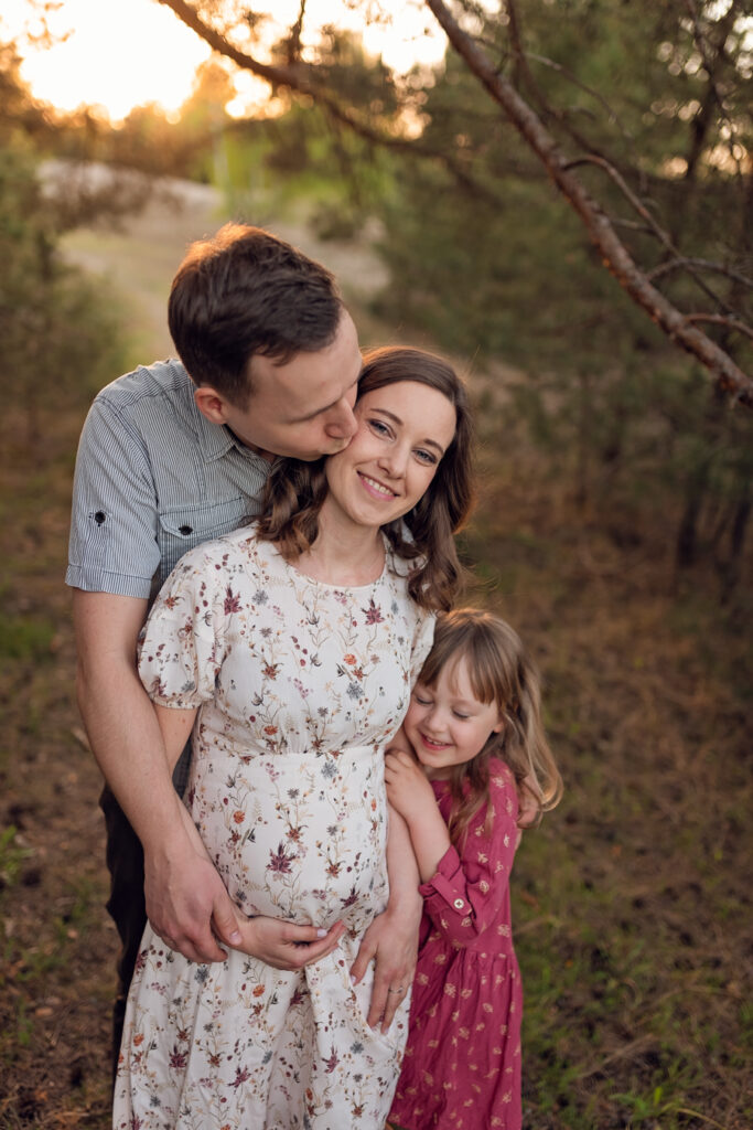 Radość oczekiwania - rodzina podczas rodzinnej sesji ciążowej w nadmorskim lasku.