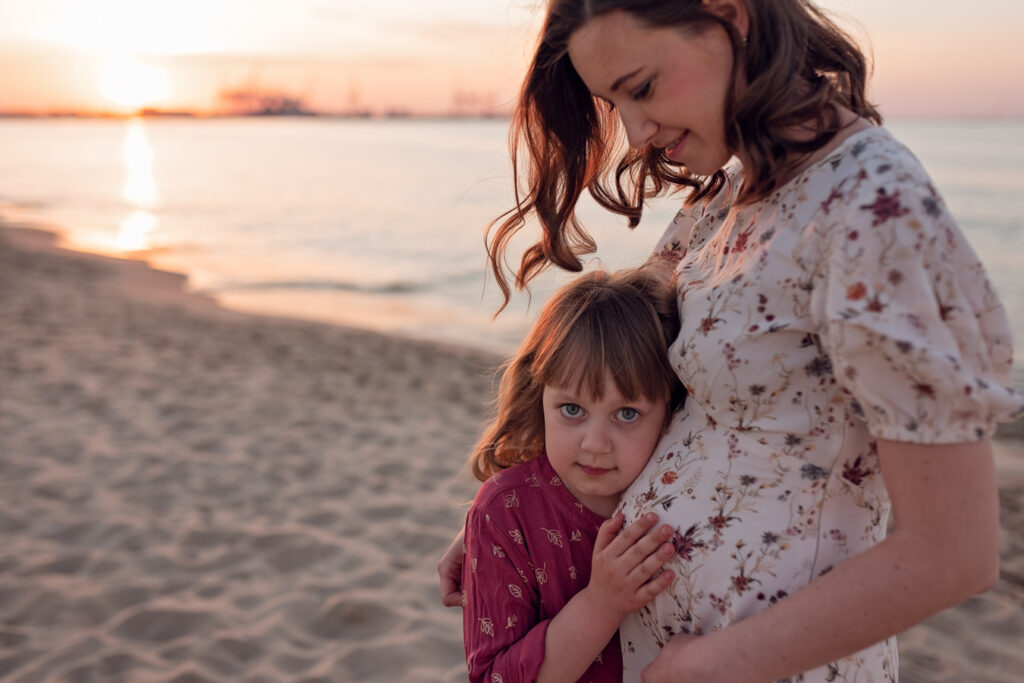 Rodzina w zachodzącym słońcu – Mama i córka ustawieni na tle zachodzącego słońca, tworzą piękną, pełną ciepła kompozycję.