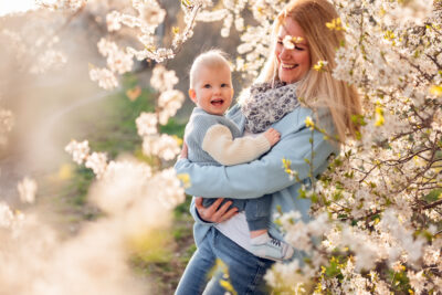 Młodzi rodzice z uśmiechem podziwiają wiosenne kwiaty podczas rodzinnej sesji zdjęciowej w Trójmieście.