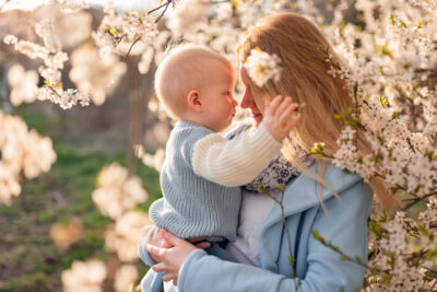 Młoda mama i jej mały syn cieszą się razem wiosennym słońcem w parku - sesja zdjęciowa rodzinna w Gdyni.