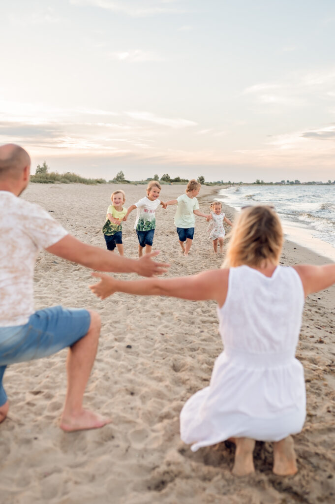 Zdjęcie z rodzinnej sesji fotograficznej na plaży w Gdyni, pokazujące radosną rodzinę