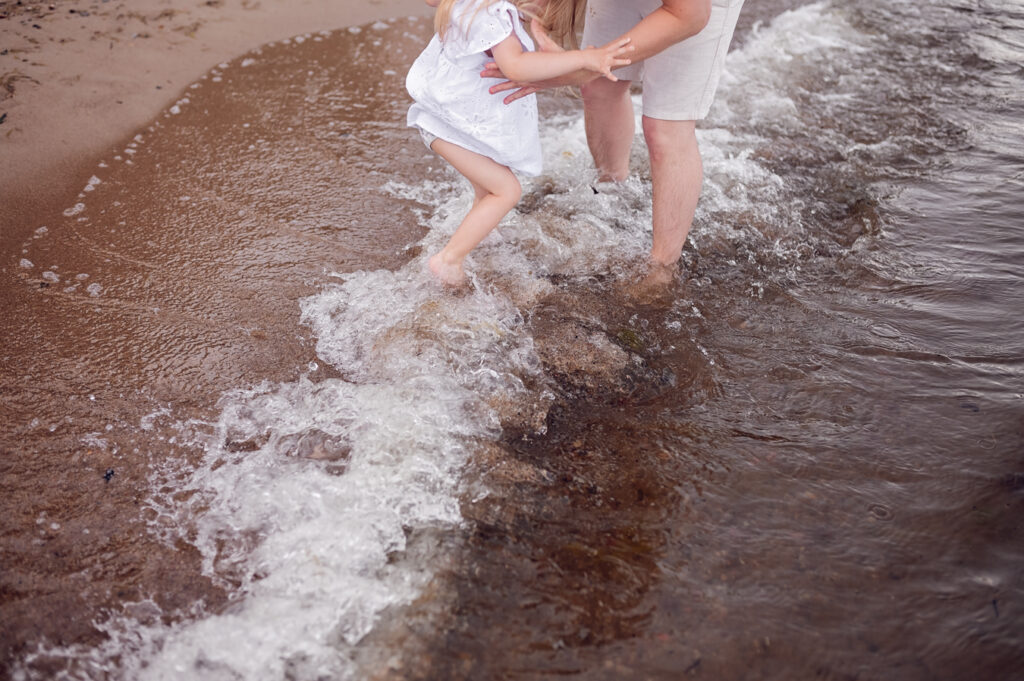 Nad brzegiem fal - dziewczynka bawiąca się w wodzie - nadmorska sesja rodzinna Trójmiasto.