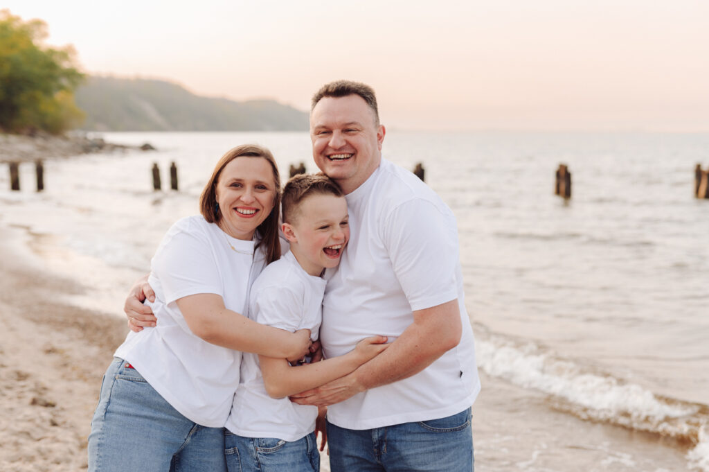 Rodzice tulący swojego roześmianego nastoletniego syna - rodzinna sesja z nastoletnimi dziecmi.