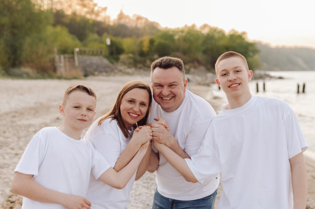 Rodzinny uścisk dłoni podczas sesji z nastoletnimi dziećmi. 