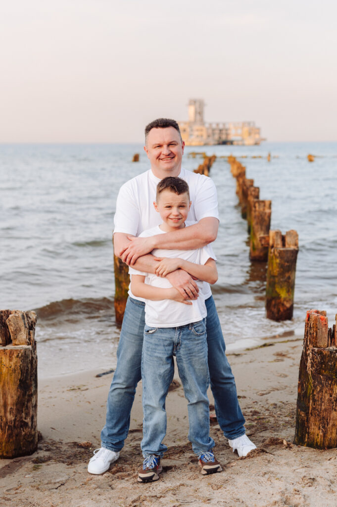 Tata z synem pozujący na plaży.