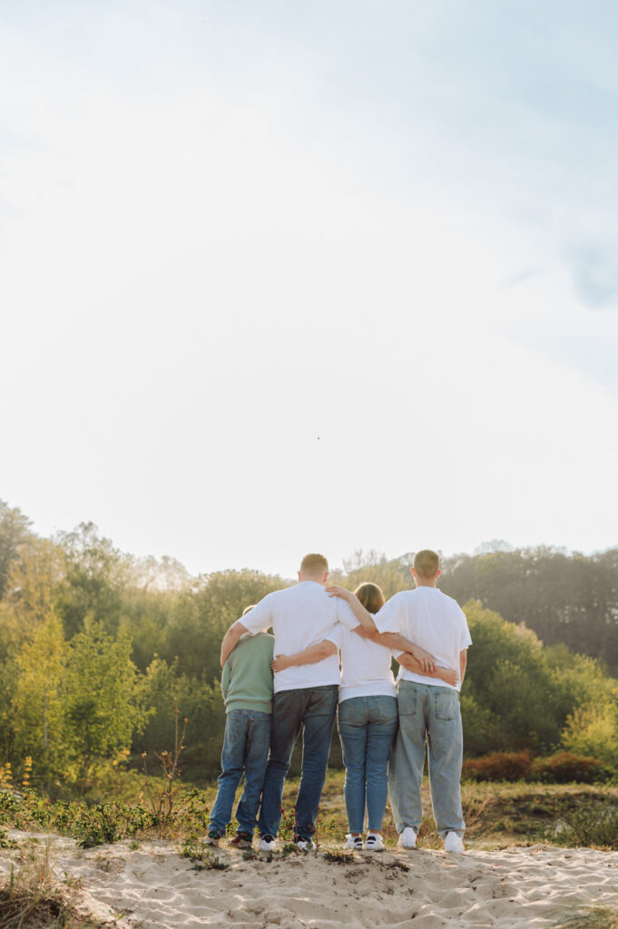 Rodzina z nastoletnimi dziećmi patrząca na zachód słońca - sesja z nastoletnimi dziećmi. 