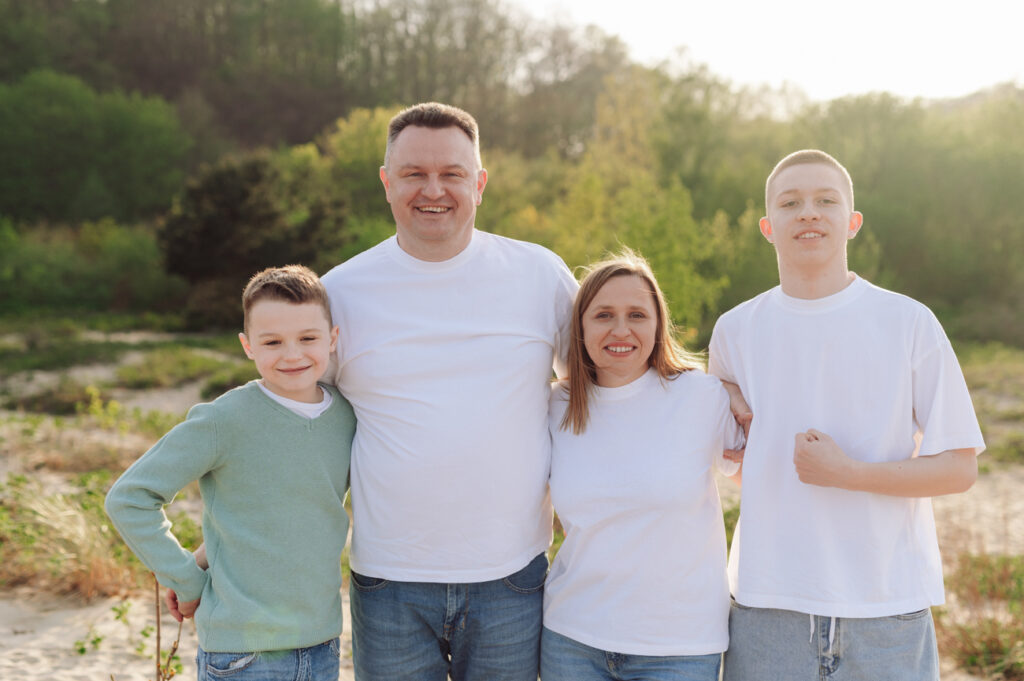Rodzina w komplecie razem z nastoletnimi chłopcami podczas sesji z nastoletnimi dziećmi na plaży.