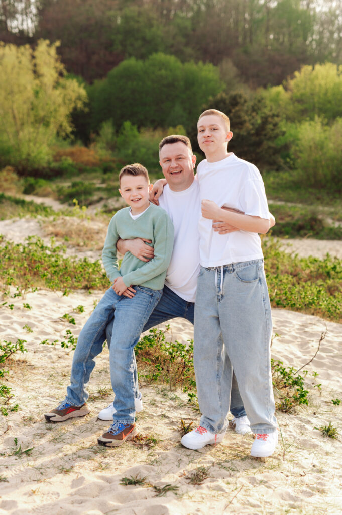 Tata z nastoletnimi synami o zachodzie słońca na plaży.